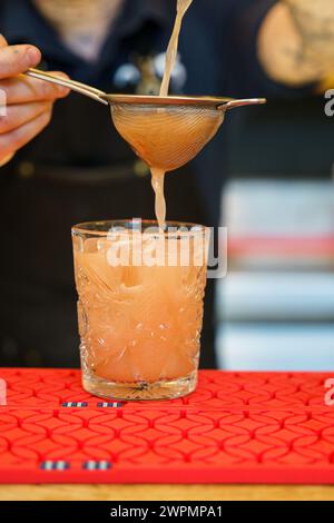 Bartender making a cocktail and pouring drink into a glass Stock Photo