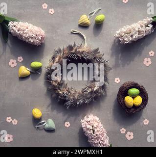 Quail feather wreath, pink hyacinth flowers, birds nest with Easter eggs, linen towel, spring background Stock Photo