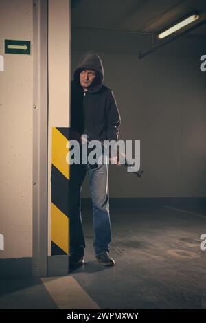 Man in black hooded shirt armed with automatic gun looking for a danger Stock Photo