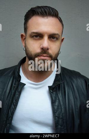 Fashionable man in a sleek leather jacket poses confidently - Embodying edgy urban style with a cool gaze Stock Photo