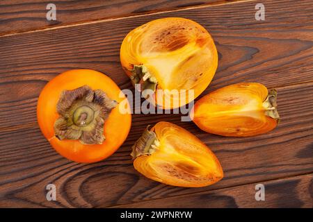 sliced persimmon on wood background top view Stock Photo