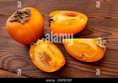 sliced persimmon on wood background Stock Photo