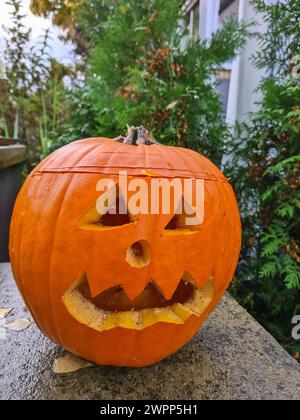 A carved pumpkin on Halloween as decoration in front of a house Stock Photo