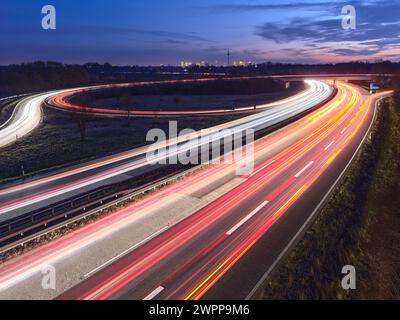 A highway in the evening with the light trails of passing cars and the Frankfurt skyline in the background Stock Photo