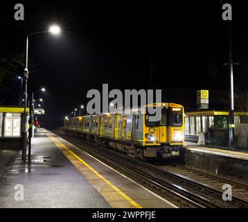 Merseyrail electrics class 507 third rail electric train 507007 at Blundellsands & Crosby railway station, Liverpool, UK at night Stock Photo