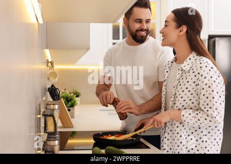 Happy lovely couple cooking together in kitchen Stock Photo