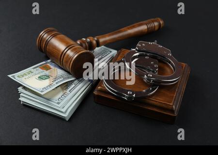 Judge's gavel, money and handcuffs on black background Stock Photo