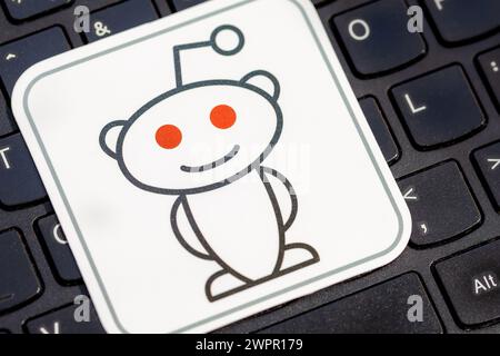 Reddit mascot logo placed on a laptop computer keyboard. Snoo Reddit social media brand symbol detail closeup, Redditors and communities on the platfo Stock Photo