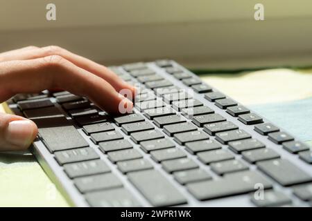 A persons hand is laying on the keys of a sleek modern design business office keyboard, suggesting writing blogging freelance work or everyday compute Stock Photo