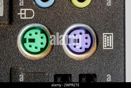 Green PS 2 port for a keyboard and a purple port for a mouse, old desktop PC obsolete unused connector standard technology used for peripheral connect Stock Photo