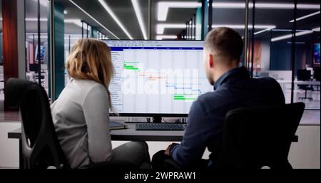 Young Businesspeople Analyzing Gantt Chart And Calendar On Computer In Office Stock Photo