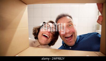 Low Section View Of A Young Happy Couple Looking Inside Cardboard Box Stock Photo