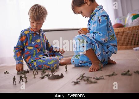 Boys, playing and kids in pajamas with toys for fun with action figures, car or games. Brothers, child development and young children bonding together Stock Photo