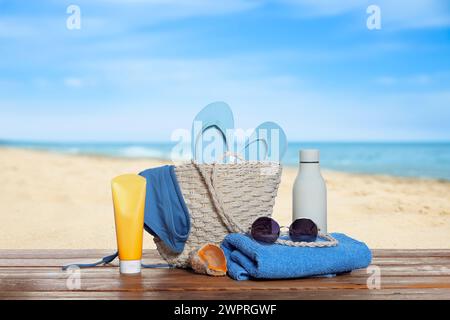 Stylish bag and other beach accessories on wooden table near sea Stock Photo