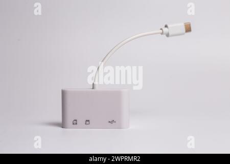 A white charger with two USB ports and an SD card reader is placed on a white surface. It serves as an electronics accessory and communication device Stock Photo