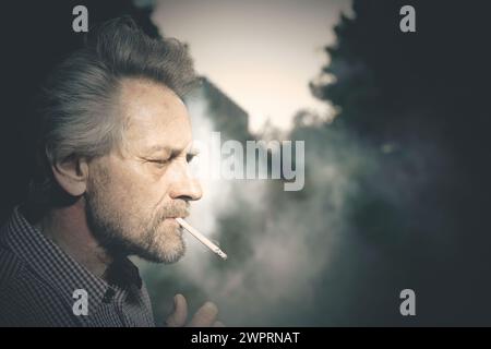 smoking a lot of cigarettes lately but inside Aged man smoking cigarettes in city park lately on day time Stock Photo