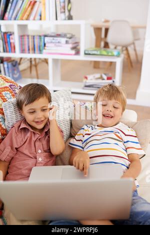 Laptop, children and siblings on a sofa with cartoon, film or streaming movie at home. Computer, learning or boy kids in a house for google it, search Stock Photo