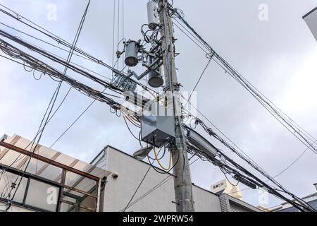 A utility pole with a lot of wires and a surveillance camera on it Stock Photo