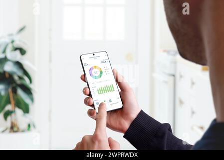 Guy monitors home electricity usage with smart home app. Concept of energy efficiency, technology, and household management for sustainable living Stock Photo