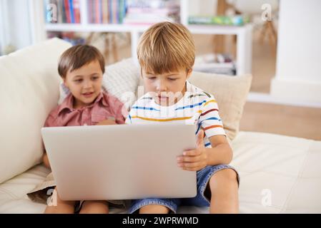Laptop, love and kid siblings on a sofa with cartoon, film or streaming movie at home. Computer, e learning or children in a living room for google it Stock Photo
