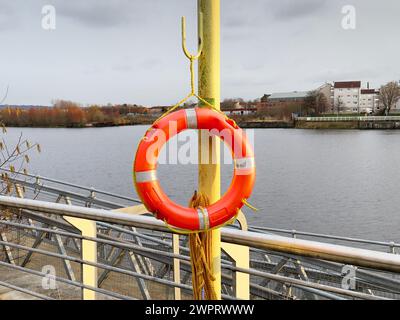 Red buoy life safety ring on post at riverbank in Glasgow Stock Photo