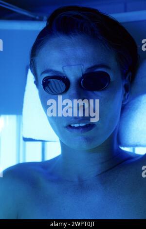 young woman portrait alternative medecine UV cabin close up face with little sunglasses to protect eyes Stock Photo