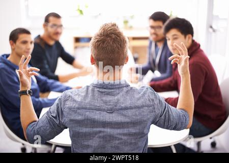 Creative man, team and meeting with presentation for startup, development or speech at the office. Rear view of speaker talking to group of developers Stock Photo