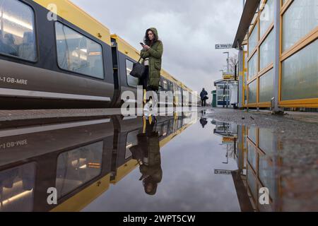 passenger boarding a Merseyrail Stadler class 777 train at  Bebington rail station reflected in a puddle on the station platform Stock Photo