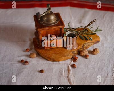 Retro coffee grinder on table with nuts and olive branch over beautiful old linen tablecloth Stock Photo