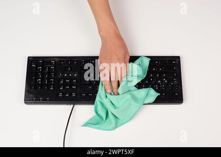 Cleaning computer keyboard in office with a wet wipe rag, dusty and dirty electronic, housework Stock Photo