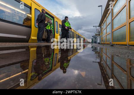 Passengers leaving and boarding a Merserail train at Bebington railway station reflected in a puddle Stock Photo