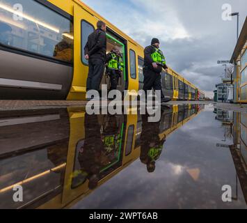 Passengers leaving and boarding a Merserail train at Bebington railway station reflected in a puddle Stock Photo