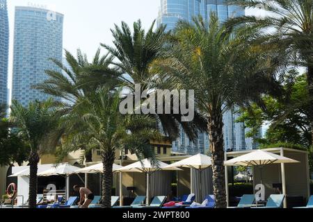 Guests lounge by the pool at Palace Downtown, with the impressive Burj Khalifa rising in the background. Dubai, UAE - August 15, 2023 Stock Photo