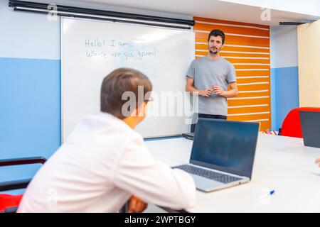 Man with down syndrome using laptop during IT teacher explanation at class Stock Photo
