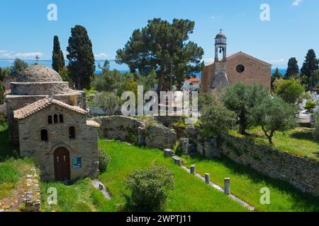 Old church surrounded by ruins in a rural area with tall cypress trees, Temple of Apollo of ancient Assinai, Byzantine fortress, nunnery, monastery Stock Photo