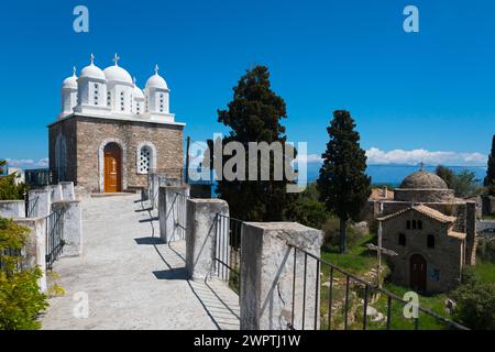 Church with classical architecture, surrounded by trees and blue sky, on the right Temple of Apollo of ancient Assina, Byzantine fortress with Stock Photo