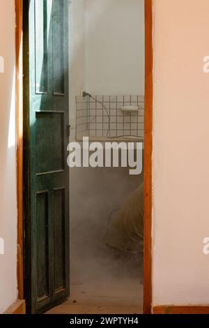 A worker cuts some concrete using a grinder, in the bathroom of a farmhouse in the eastern Andean mountains of central Colombia, producing some dust. Stock Photo