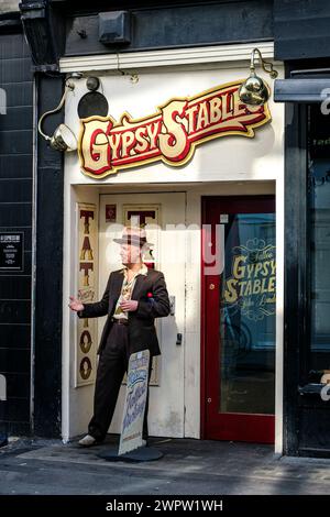 Soho, London UK, March 08 2024, Man Standing In Doorway Of Gypsy Stables Tattoo Studio Berwick Street Stock Photo