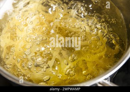 Noodles cooking inside a stainless steel pot filled with boiling water bubbling at 100 degrees Celsius. Stock Photo