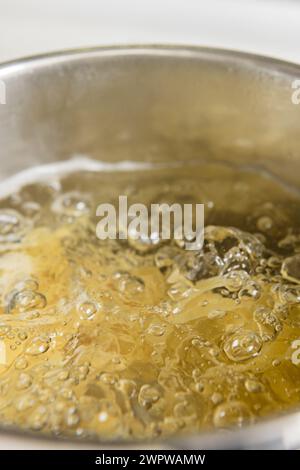 Wheat noodles cooking inside a stainless steel pot filled with water in a home kitchen Stock Photo