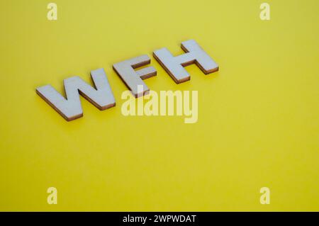 WFH wooden letters representing Work From Home on yellow background. Stock Photo