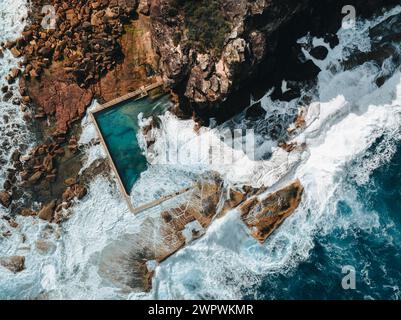 Aerial view early morning light with ocean waves flowing over rocks around North Curl Curl ocean rock pool during storm. Stock Photo