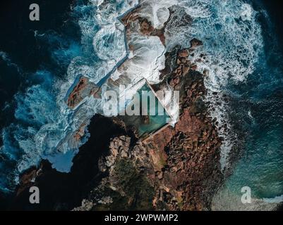 Aerial view early morning light with ocean waves flowing over rocks around North Curl Curl ocean rock pool during storm. Stock Photo