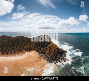 Byron Bay lighthouse high on the rocky headland - the most eastern point of Australian continent facing Pacific ocean in elevated aerial seascape Stock Photo