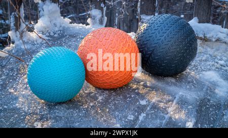 heavy slam balls filled with sand on an icy backyard deck, exercise and functional fitness concept Stock Photo