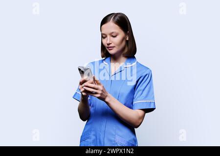 Young female nurse using smartphone, on white background Stock Photo