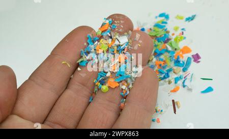 Close-up on many microplastic particles in human hand. Concept of plastic pollution with nanoplastics. Soft focus on a micro plastic particles Stock Photo