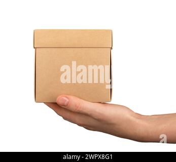 Kraft carton box, cardboard package of square shape in hand, isolated on white. Stock Photo