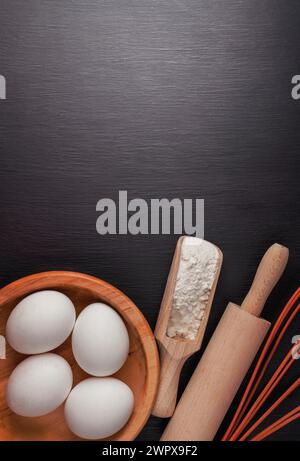 Baking background with ingredients for making gingerbread : flour, eggs, kitchen tools, utensils and on dark wooden table. Top view. Flat lay style. M Stock Photo