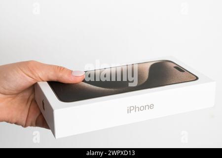 BERLIN , GERMANY - FEBRUARY 14 2024: IPhone box in womans hand on a white background. A gift concept.  Stock Photo